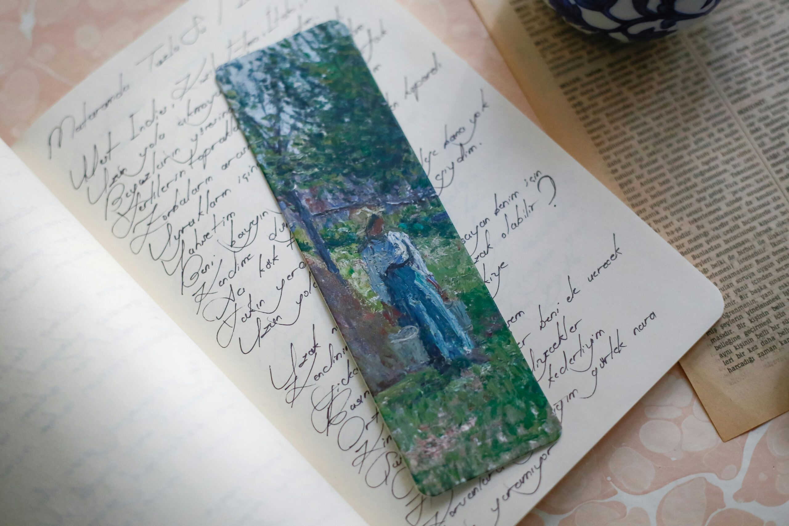 A vibrant artistic bookmark placed in an open notebook showcasing elegant handwriting.